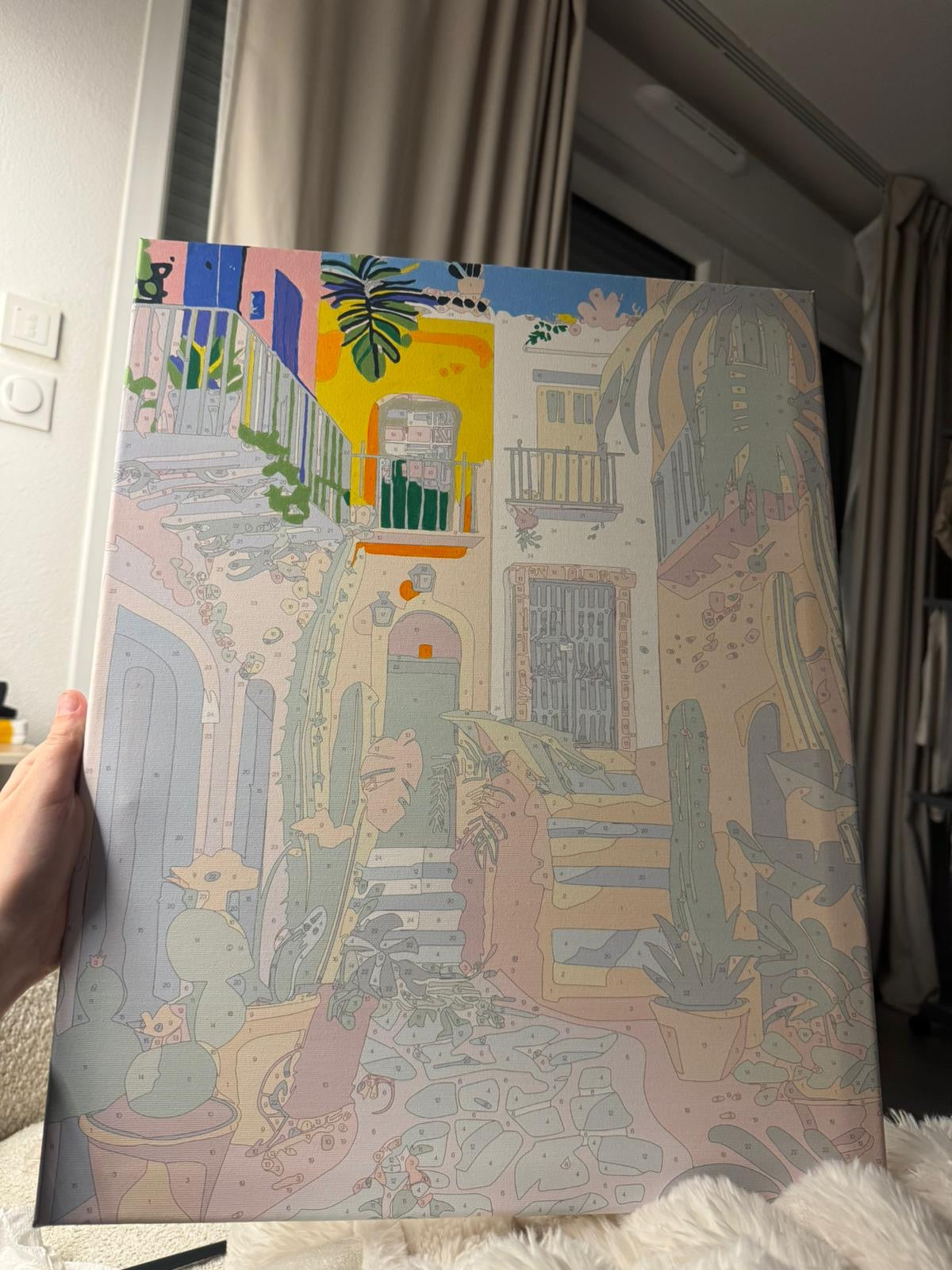 Tableau de ruelle colorée en cours de peinture, tenu par une main