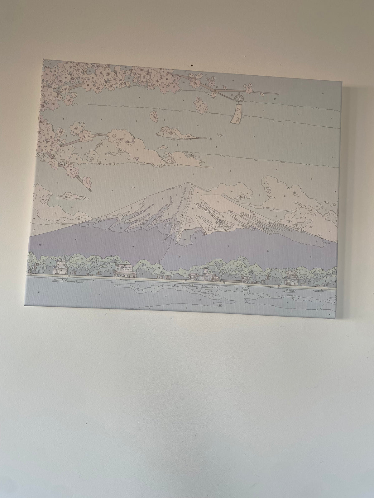 Toile représentant une montagne et des branches fleuries, accrochée au mur.