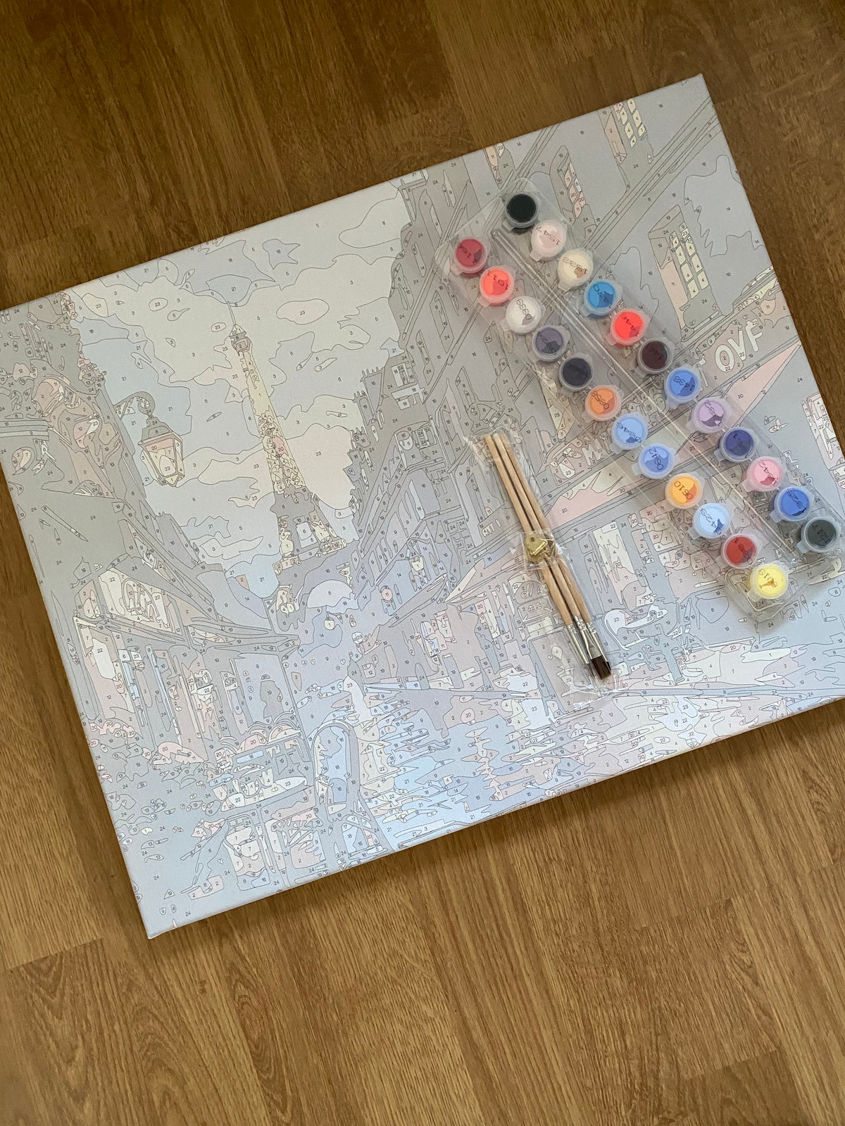 Toile numérotée photographiée avec ses pinceaux et ses pots de peinture.