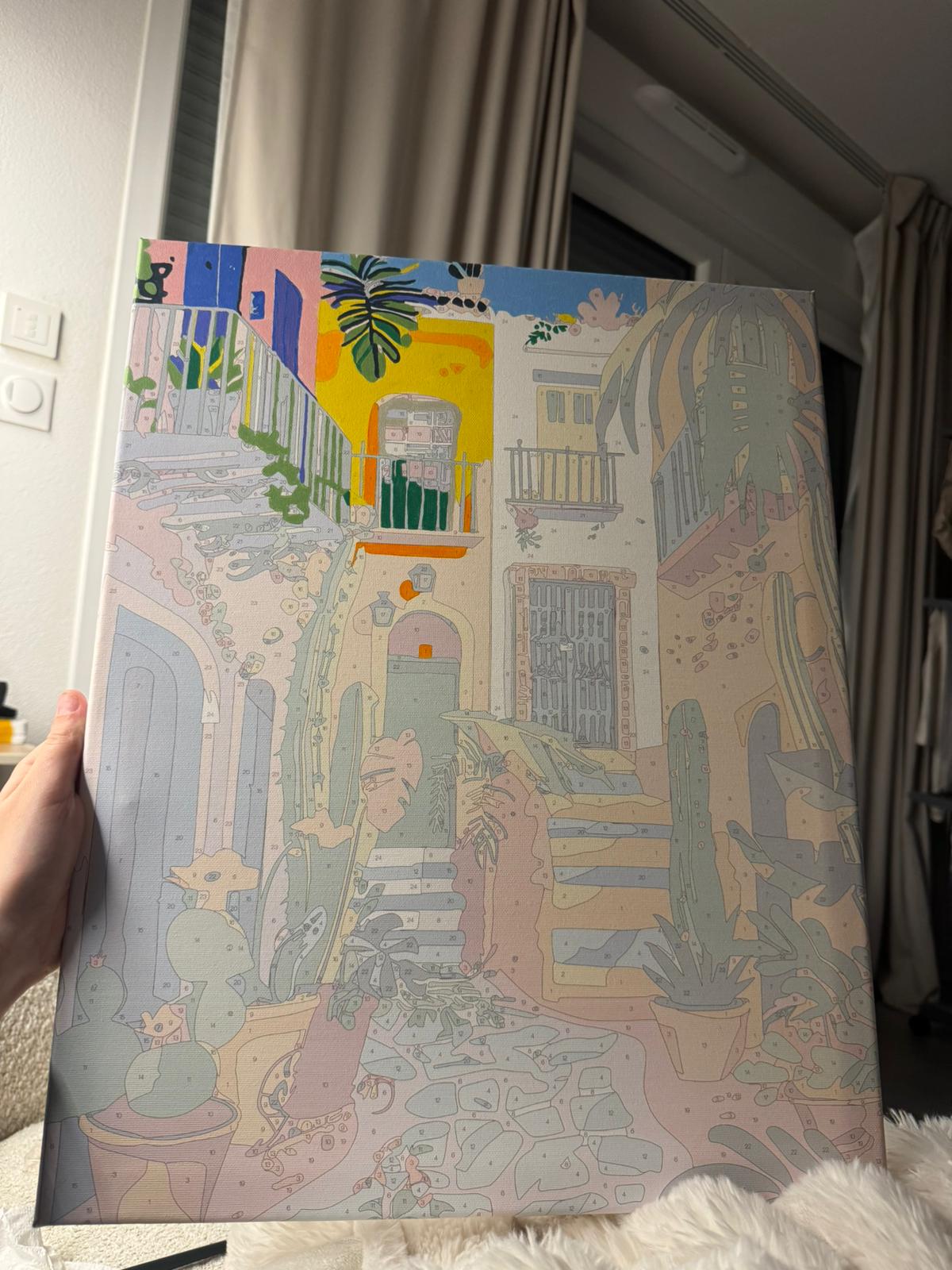 Toile de ruelle méditerranéenne tenue près d’une fenêtre.
