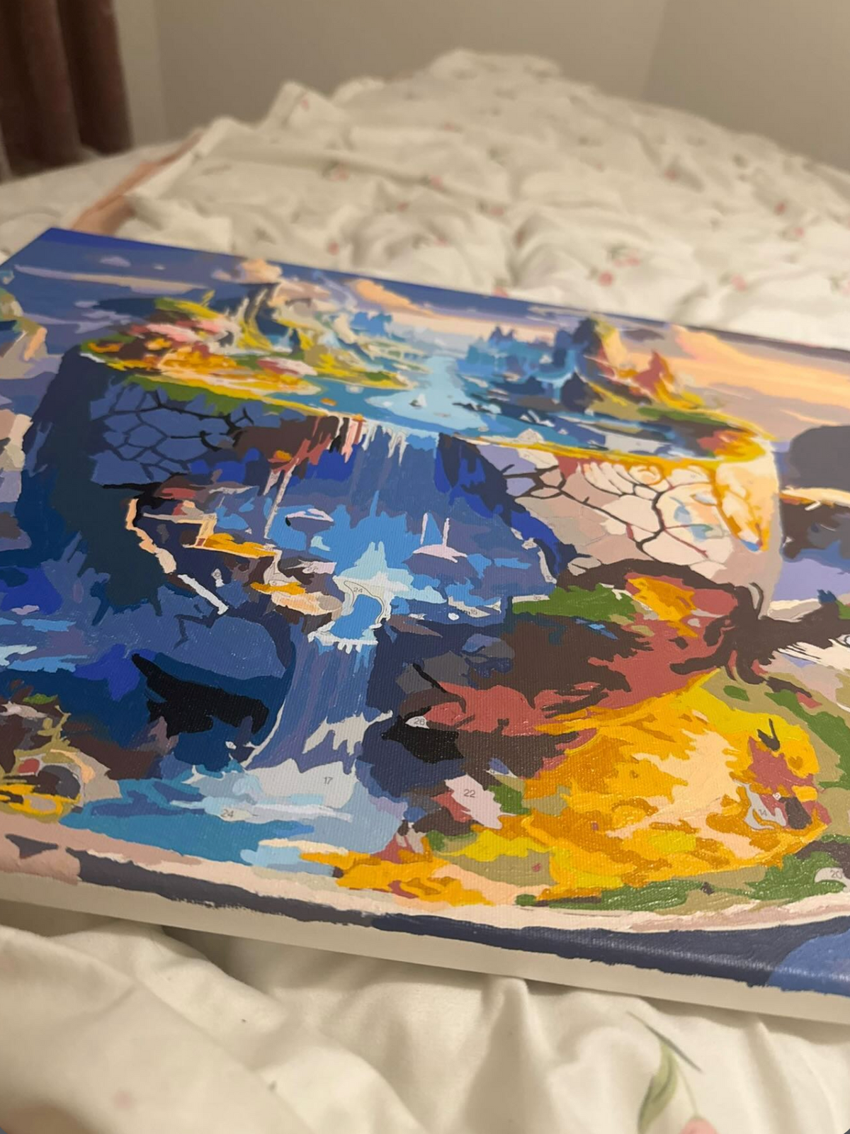 Tableau imaginaire de montagnes dans une tasse, posé sur un lit.