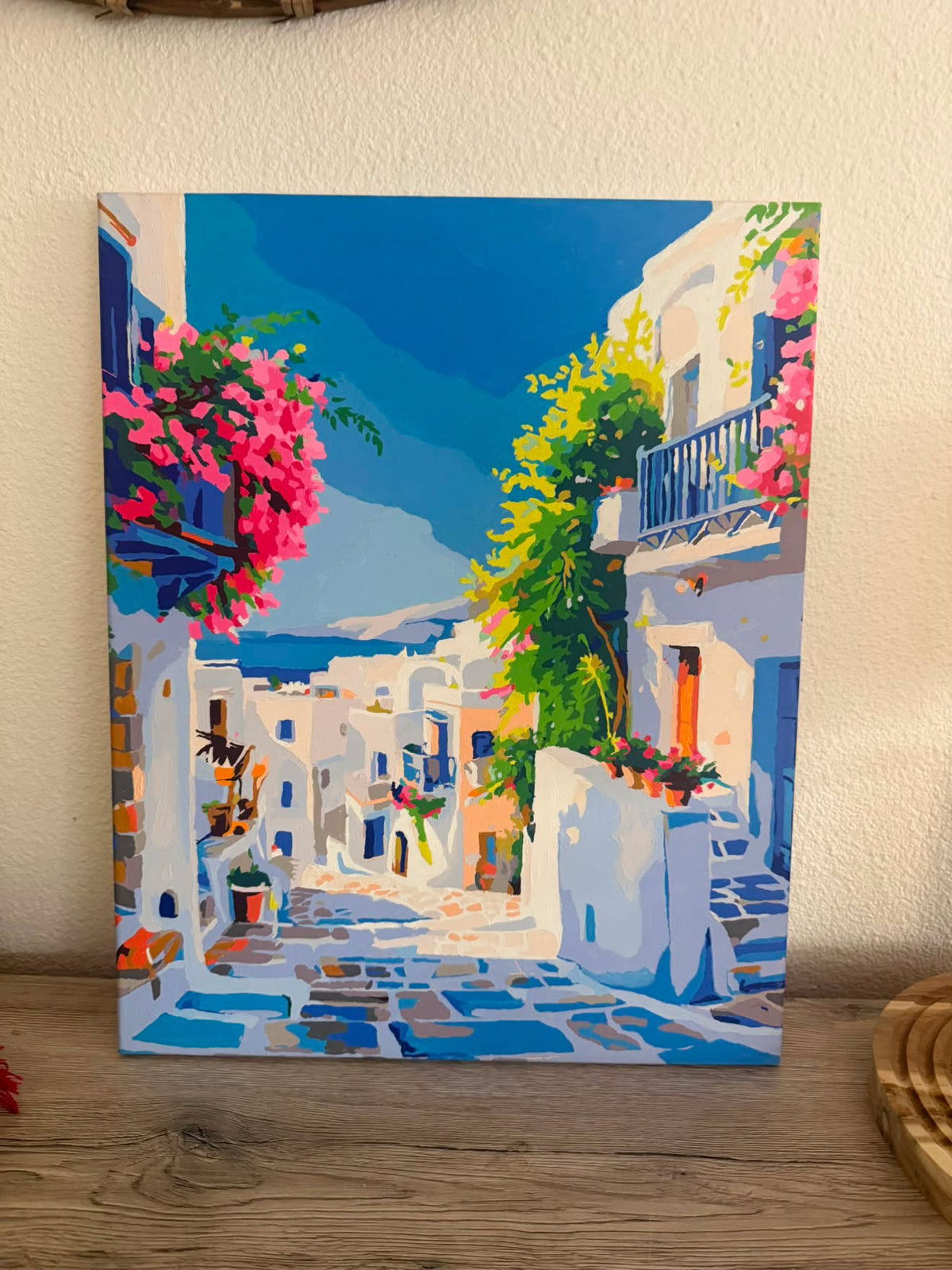 Tableau de ruelle méditerranéenne aux fleurs roses, présenté dans un intérieur